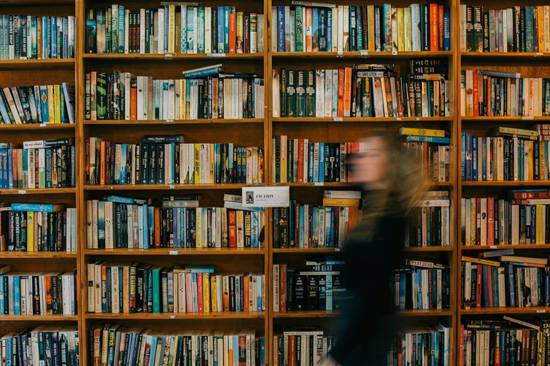 Croatian author standing in front of tall bookshelves holding a leather notebook